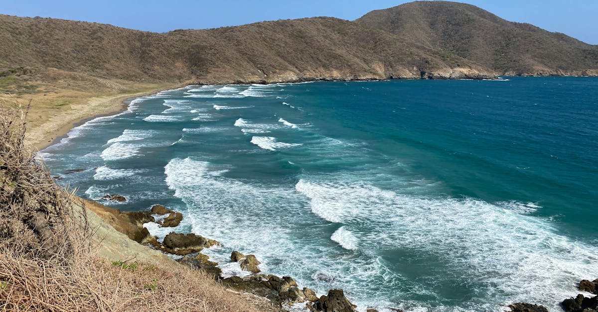 Breathtaking view of Santa Marta's coastline with waves crashing on rocky shores under a clear blue sky.
